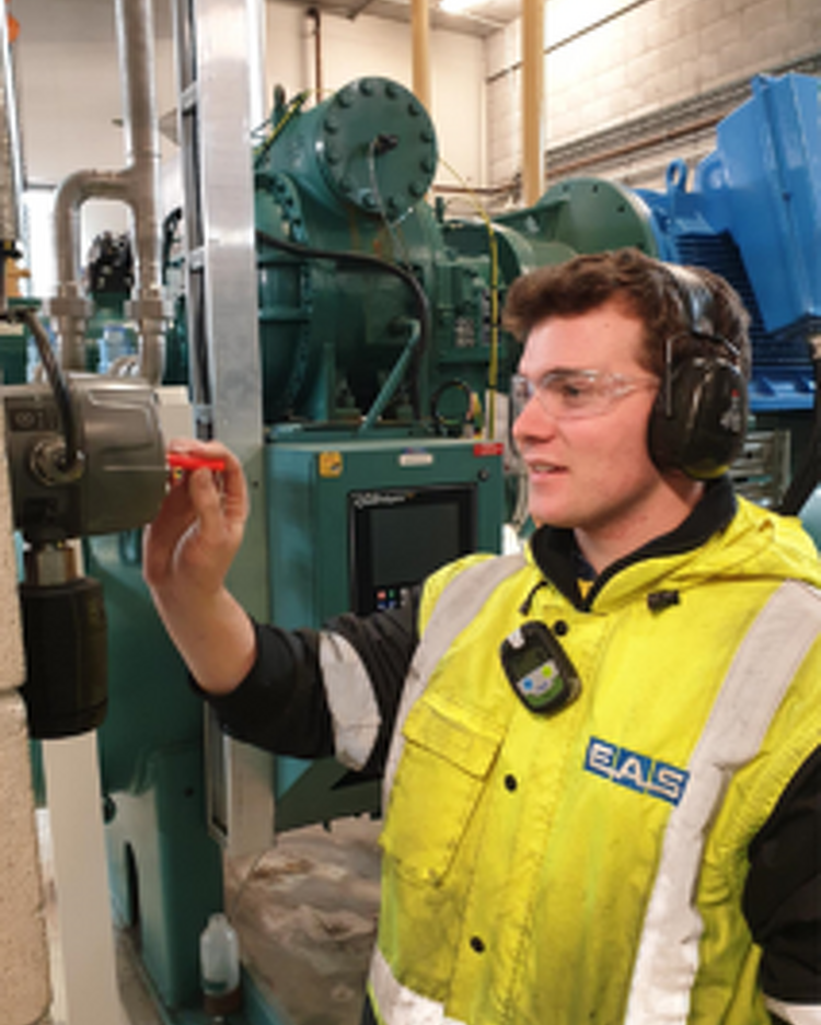 Technician adjusting a valve on an industrial refrigeration compressor unit