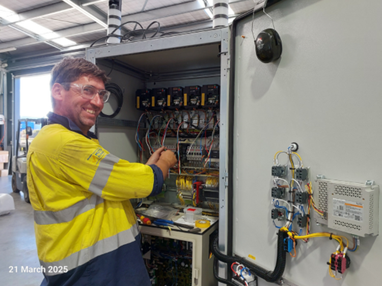 Electrician wiring a switchboard cabinet in an industrial plant