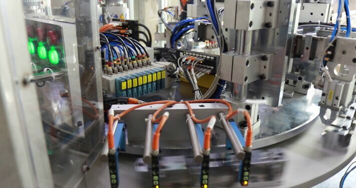 Close-up of an automated assembly machine with wiring and pneumatic components