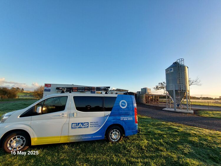 EAS Waikato van parked beside a feed silo on a farm at sunrise